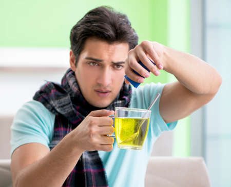 Young handsome man suffering from illness at homeの写真素材