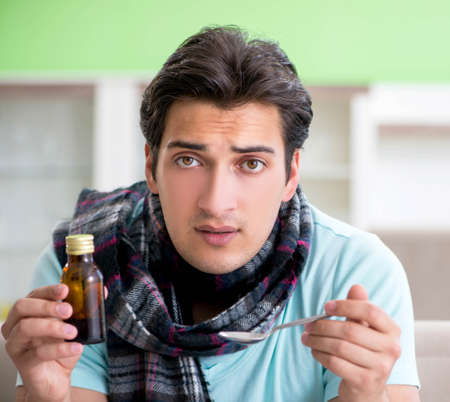Young handsome man suffering from illness at homeの写真素材