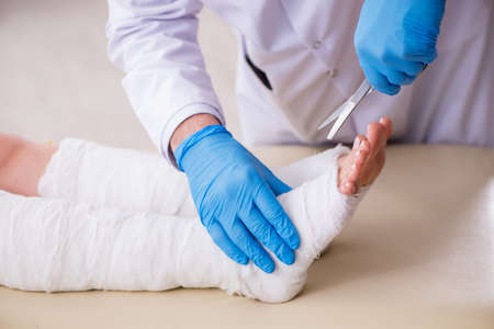 Young injured woman visiting old doctor traumatologistの写真素材