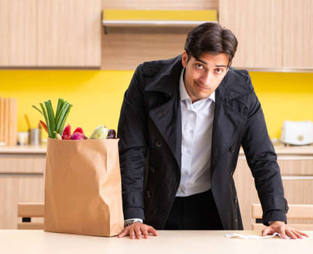Young handsome man with vegetables in kitchenの写真素材