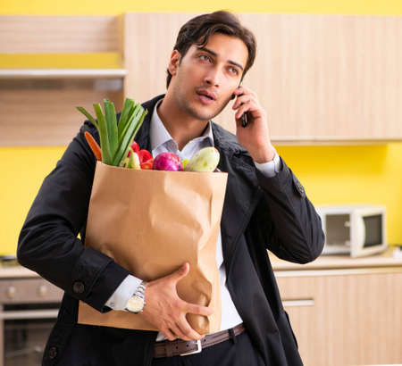 Young handsome man with vegetables in kitchenの写真素材