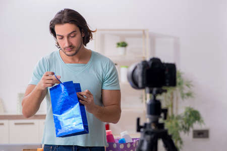 Young male shopaholic recording video for his blogの写真素材