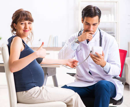 Young doctor checking pregnant womans blood pressureの写真素材