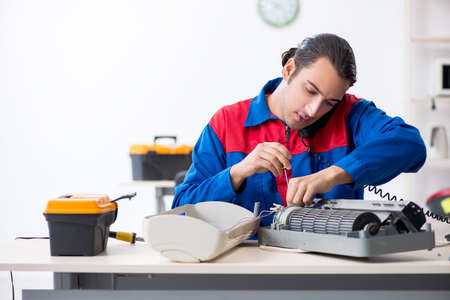 Young repairman repairing air-conditioner at warranty centerの写真素材