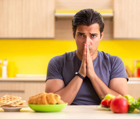 Man having hard choice between healthy and unhealthy foodの写真素材
