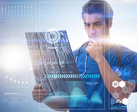 Young doctor looking at x-ray image in mhealth conceptの写真素材