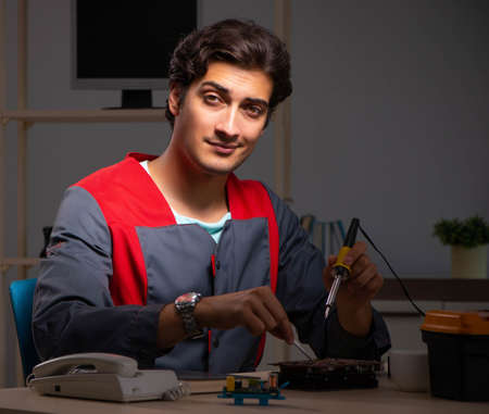 Young handsome repairman repairing computer