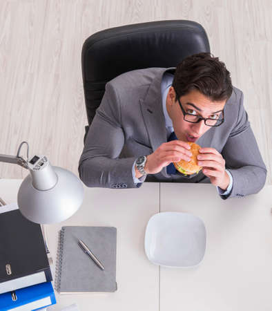 Hungry funny businessman eating junk food sandwichの写真素材