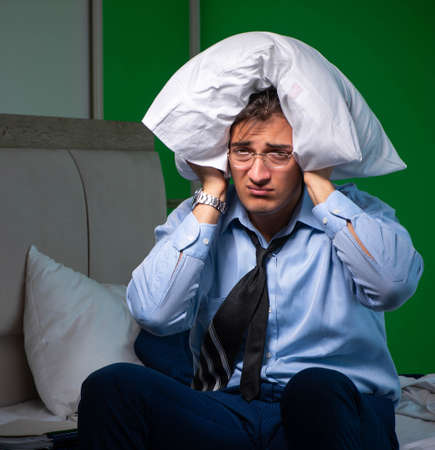 Young businessman under stress in the bedroom at nightの写真素材