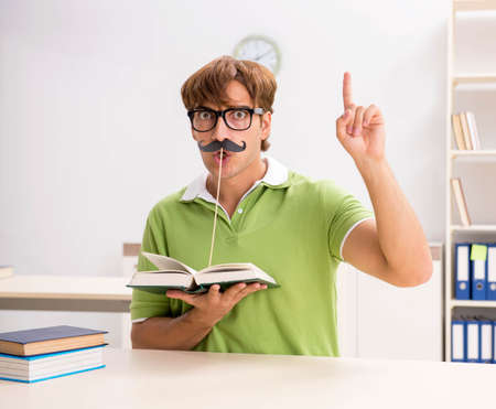 Student with fake moustache reading bookの写真素材