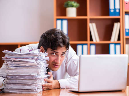 Young handsome businessman unhappy with excessive workの写真素材