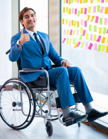 Young handsome man in wheelchair with many conflicting prioritieの写真素材