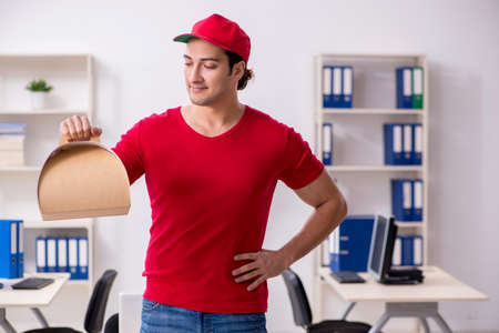Young male courier delivering cake to the officeの写真素材