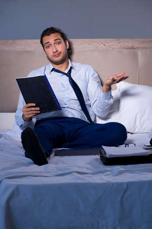 Tired businessman working overtime at home at nightの写真素材