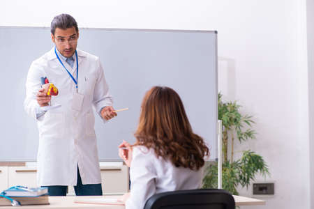Young male doctor cardiologist and female student in the classro