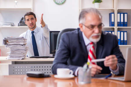 Old boss and young male employee in the officeの写真素材