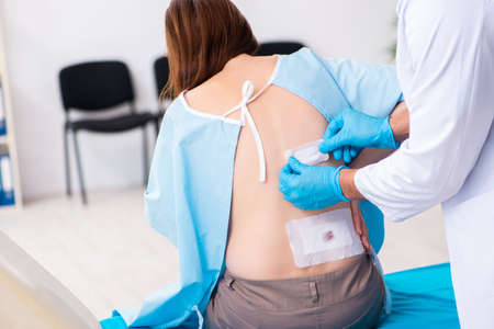 Injured young woman visiting male doctorの写真素材