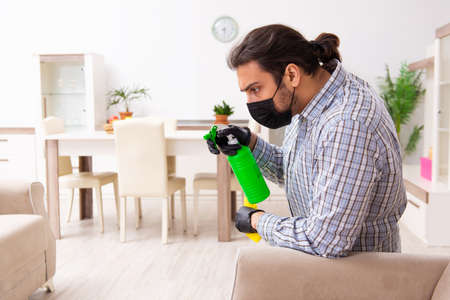Young male contractor cleaning the house in coronavirus conceptの写真素材