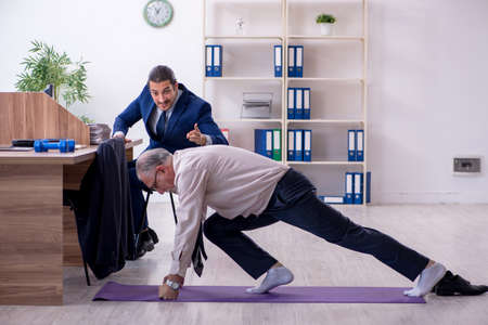 Two employees doing physical exercises at workplaceの写真素材