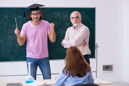 Old chemist teacher and two students in the classroomの写真素材
