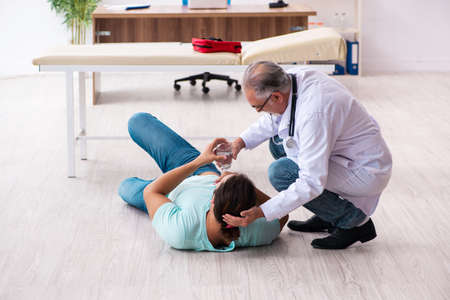 Old experienced doctor and young male patient lying on the floor