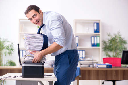 Young male employee making copies at copying machine