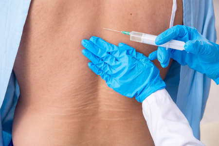 Young injured man visiting female doctor chiropractor