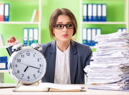 Young female employee very busy with ongoing paperwork in time mの写真素材
