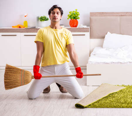 Young handsome man cleaning in the bedroomの写真素材