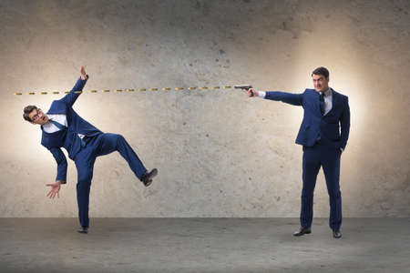 Businessman with gun threatening his competitorの写真素材