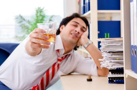 Young businessman employee drinking in the officeの写真素材
