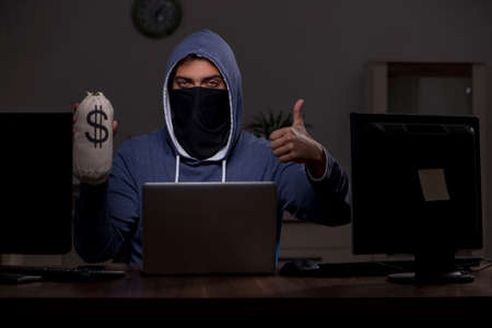 Male hacker hacking security firewall late in officeの写真素材