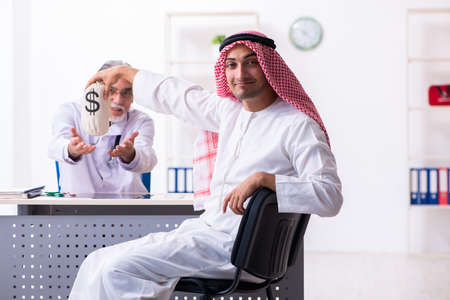 Young male arab visiting experienced male doctorの写真素材