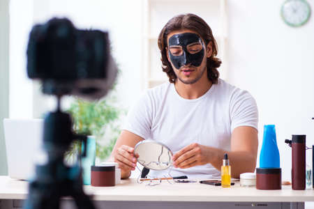 Young male cosmetician recording video for his blogの写真素材