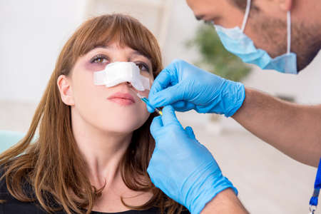 Young beautiful woman visiting doctor in plastic surgery conceptの写真素材