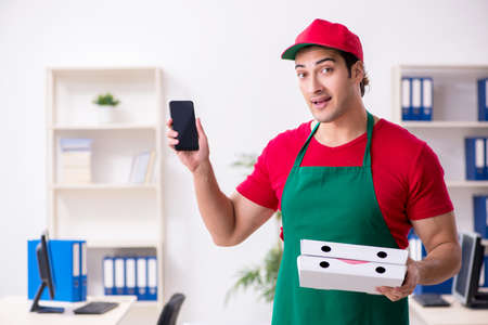 Young male courier delivering pizza to the officeの写真素材