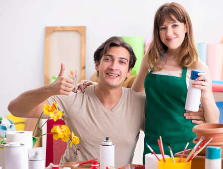 Couple decorating pots in workshop during classの写真素材