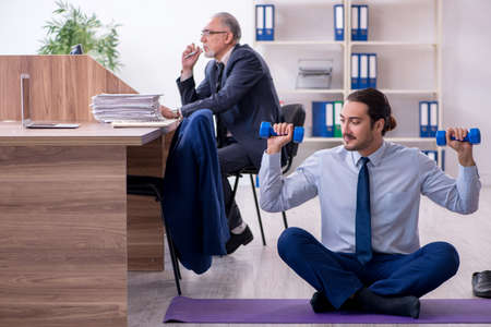 Two employees doing physical exercises at workplaceの写真素材