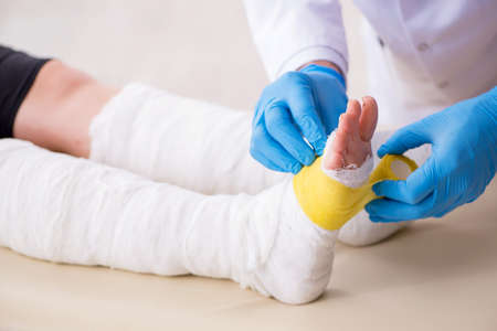 Young leg injured woman visiting old doctor traumatologistの写真素材