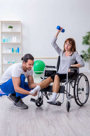 Woman in wheel-chair doing sport exercises with personal coachの写真素材