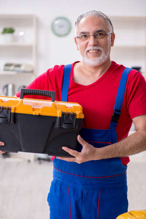 Old male contractor repairing household devices indoorsの写真素材
