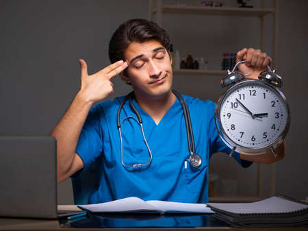 Young handsome doctor working night shift in hospitalの写真素材