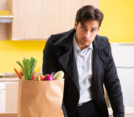 Young handsome man with vegetables in kitchenの写真素材