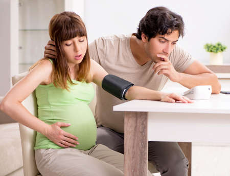 Husband checking pregnant wifes blood pressureの写真素材