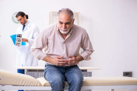 Old patient visiting young male doctorの写真素材