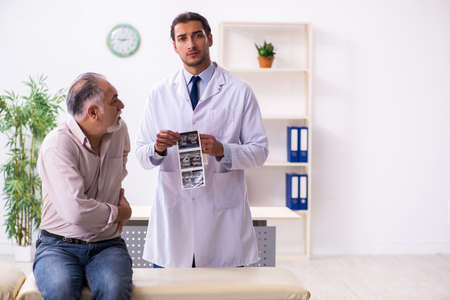 Old patient visiting young male doctorの写真素材