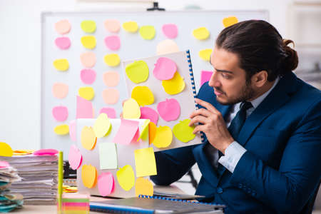 Young male employee in conflicting priorities conceptの写真素材