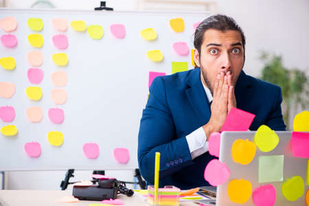 Young male employee in conflicting priorities conceptの写真素材