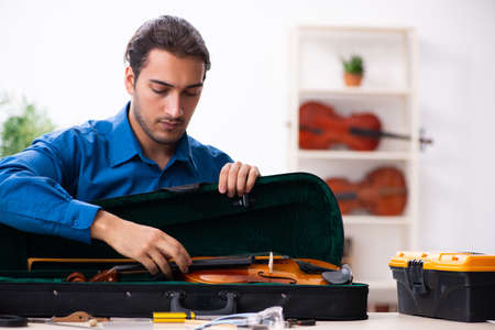 Young male repairman repairing violinの写真素材