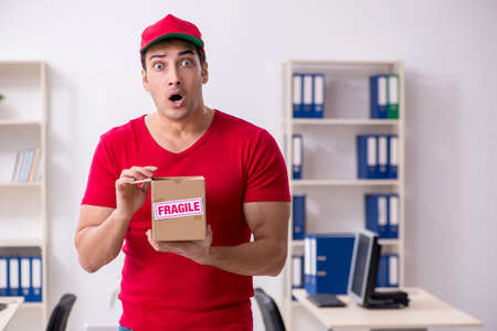 Young male courier delivering postbox to the office